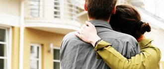 A young couple hugging and looking at a yellow house