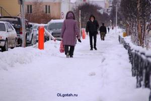 Прохожие идут по тротуару зимой